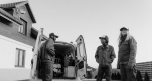 grayscale photo of people wearing coveralls standing beside a service van
